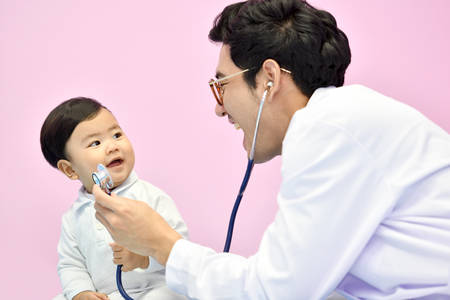 Asian pediatrician examining a baby with a stethoscope in a hospitalの写真素材