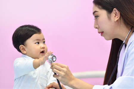 Asian pediatrician examining a baby with a stethoscope in a hospitalの写真素材