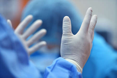 Surgeon hand putting on a grove and preparing for a surgeryの写真素材