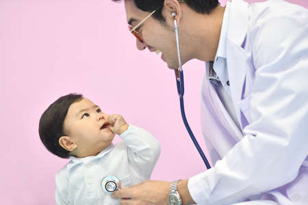Asian pediatrician examining a baby with a stethoscope in a hospitalの写真素材
