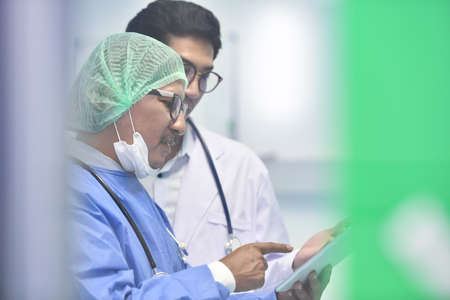 Asian surgeon team using digital tablet at work in operating roomの写真素材