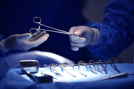 Surgeon hand picking up an instrument from tray of surgical instrumentsの写真素材