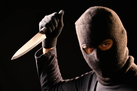 The robber hold the knife in hand on black backgroundの写真素材