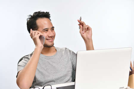 Casually-dressed startup business man smiling while talking on the phone and having fun at work