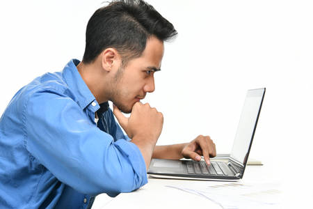 Casually-dressed startup business man sitting in relaxed posture while working with laptop computer
