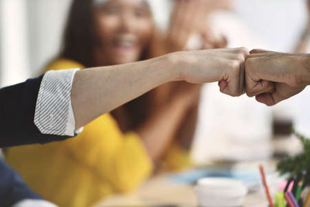 Image of 2 businesspersons fist-bumping in agreement at a meeting at officeの写真素材