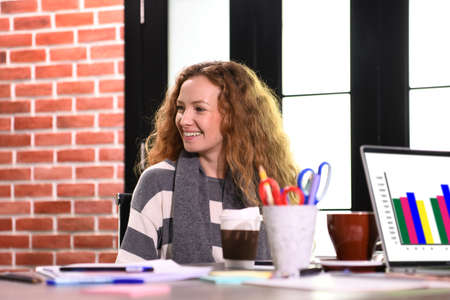 Portrait of a smiling young businesswoman sitting at the desk in an office