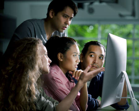 Group of young businesspersons looking intently at the screen with shock anxious and worried...