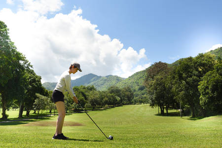 Young Asian woman playing golf on a beautiful natural golf course