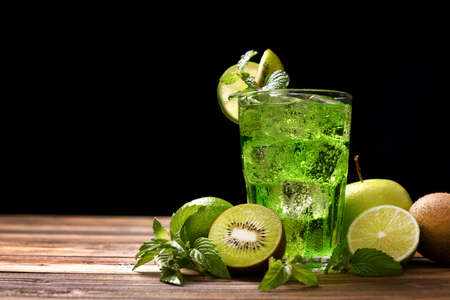 Sweet lime and kiwi soda with sliceed fruits on wooden table on black backgroundの写真素材