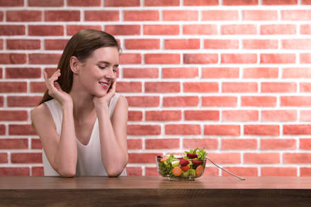 Beautiful young woman in joyful postures with salad bowlの写真素材
