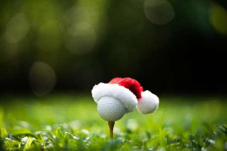 Festive-looking golf ball on tee with Santa Claus' hat on top for holiday season on golf couse backgroubdの写真素材