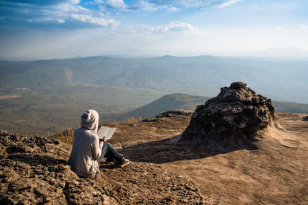 A woman sitting and reading  looking out at beaitiful natural viewの写真素材