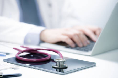 Medical doctor working on computer in examination room
