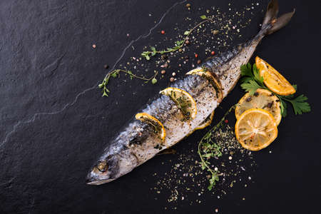Grilled fish and various vegetables on black stoneの写真素材