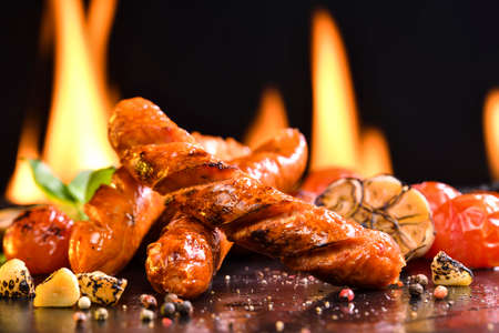 Grilled sausages and various vegetables on black stone