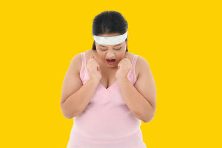 Overweight Asian woman looking shocked to see the weight on the scaleの写真素材