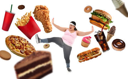Overweight Asian woman fighting off junk food isolated on white backgroundの写真素材