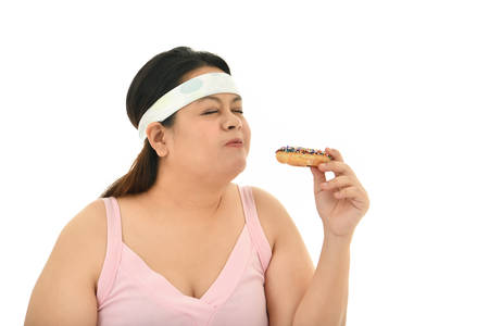 Overweight Asian woman enjoy eating junk food isolated on white backgroundの写真素材
