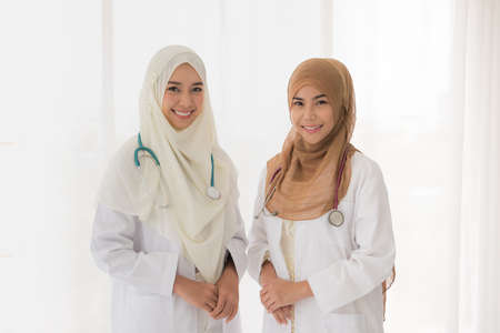 Portrait of two muslim female doctor working at office and smiling at cameraの写真素材