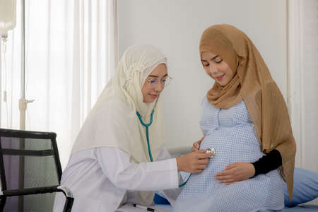 Pregnant muslim woman with her muslim female doctor in clinic, Gynaecology consultation
