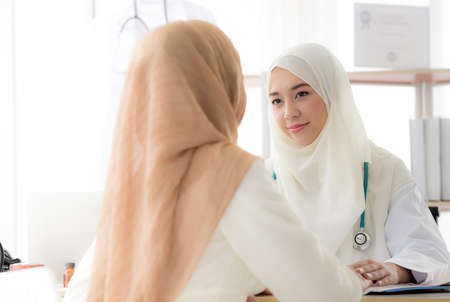 Muslim woman patient having consultation with female muslim doctor In clinicの写真素材