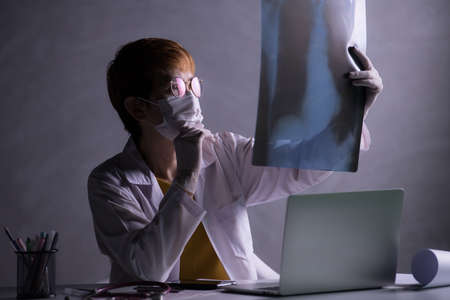 Medical doctor looking worried when inspecting x-ray film of lungs during COVID-19 pandemic outbreak...