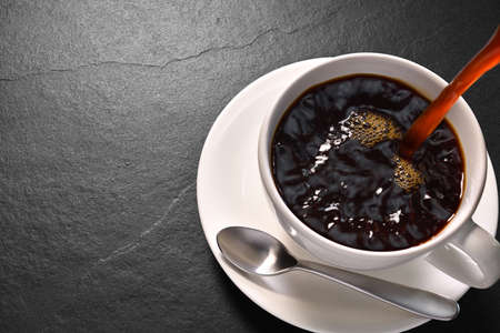 Pouring coffee with smoke on a cup on black background