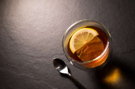 Top view image of a cup of tea with lemon on black granite backgroundの写真素材