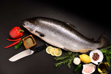 Top view of fresh whole salmon fish seafood on black stone backgroundの写真素材