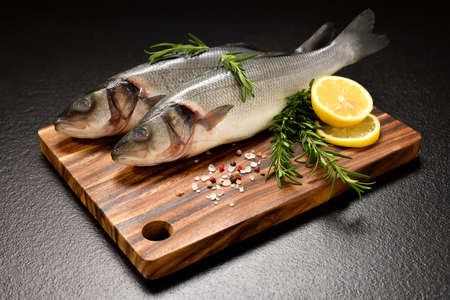 Fresh seafood Sea Bass fish arranged on black stone backgroundの写真素材