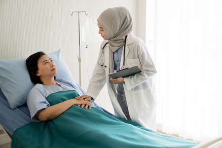 Asian female muslim doctors examination and treating patient in a hospital roomの写真素材