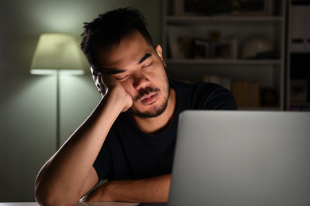 Overworked tired, Asian businessman sleeping while using computer working late at night at homeの写真素材