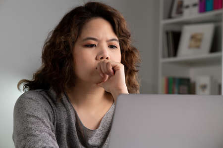 Feeling tired and stressed. Young Asian woman sitting looking deep in thought exhausted and tired...