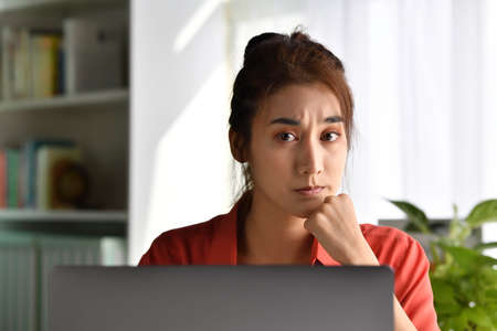 Feeling tired and stressed. Young Asian woman sitting looking deep in thought exhausted and tired...