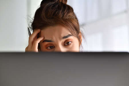 Feeling tired and stressed. Young Asian woman sitting looking exhausted and tired during working at...