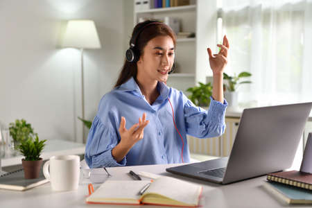 Feeling good happy and positive at work. Young Asian businesswoman wearing headset on video call...