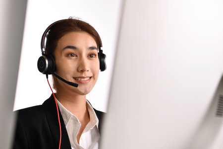 Asian woman call center working use headset look at computer screen. Portrait of smiling Asian...