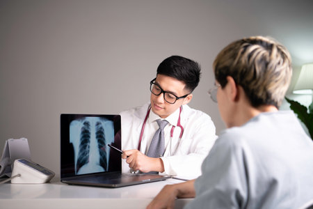Kind and polite young Asian medical doctor orthopedic surgeon wearing stethoscope showing x-ray...