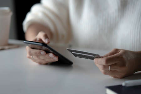 Female hands holding credit card and using smartphone. Online shoppingの写真素材