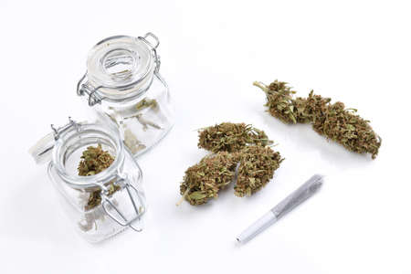Medical cannabis flowers and marijuana joint on white table and in containers in clean laboratory setting for home consumption research and inspection for medicinal and recreational properties isolated on white backgroundの写真素材