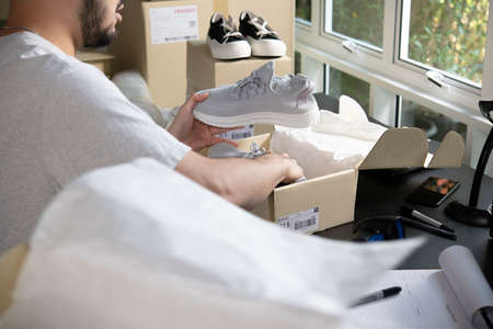 Male online store small business owner entrepreneur packing package post shipping box preparing delivery parcel on table. E-commerce drop shipping shipment service concept.の写真素材