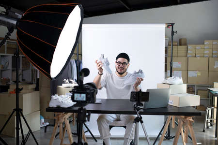 Young attractive Asian man blogger or vlogger looking at camera reviewing product. Modern...