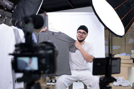 Young attractive Asian man blogger or vlogger looking at camera reviewing product. Modern...