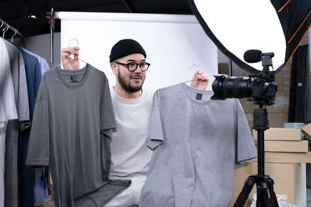Young attractive Asian man blogger or vlogger looking at camera reviewing product. Modern...