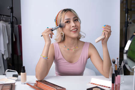 Young beautiful Asian woman and professional beauty make up artist vlogger or blogger recording makeup tutorial to share on website or social media. Business online influencer on social media concept.の写真素材