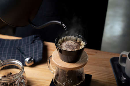 Cup of coffee with smoke and coffee beans on old wooden background