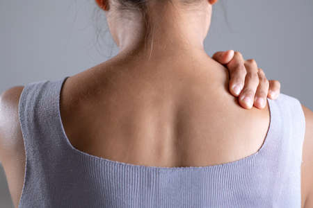 Asian woman has shoulder pain. Female holding painful shoulder with another hand. People with...