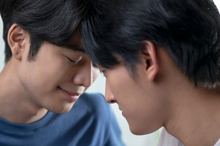 Image of young pleased Asian gay men with closed eyes and teardrop touching each other face to face. Idea of homosexual relationship, tenderness and closeness. LGBT couple lifestyle concept.の写真素材