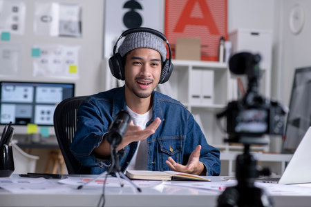 Young Asian male graphic designer blogger influencer talking looking at camera shooting education tutorial vlog training filming video course for social media at studio.の写真素材